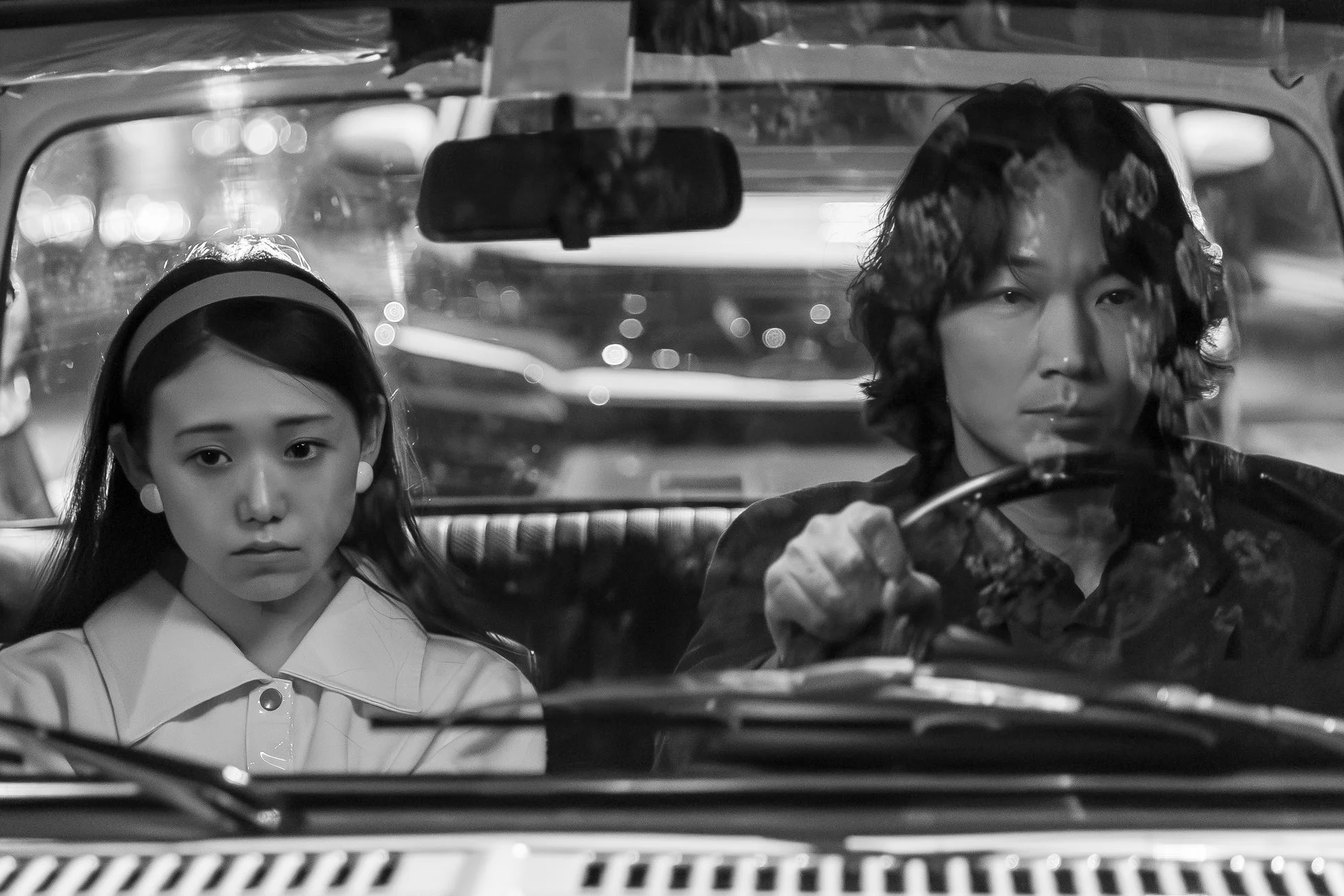 夜の車内で真剣な表情の男女