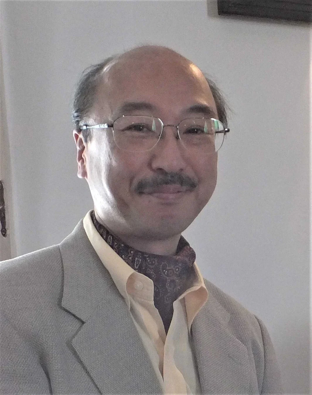 眼鏡と口ひげが特徴的な中高年のアジア人男性