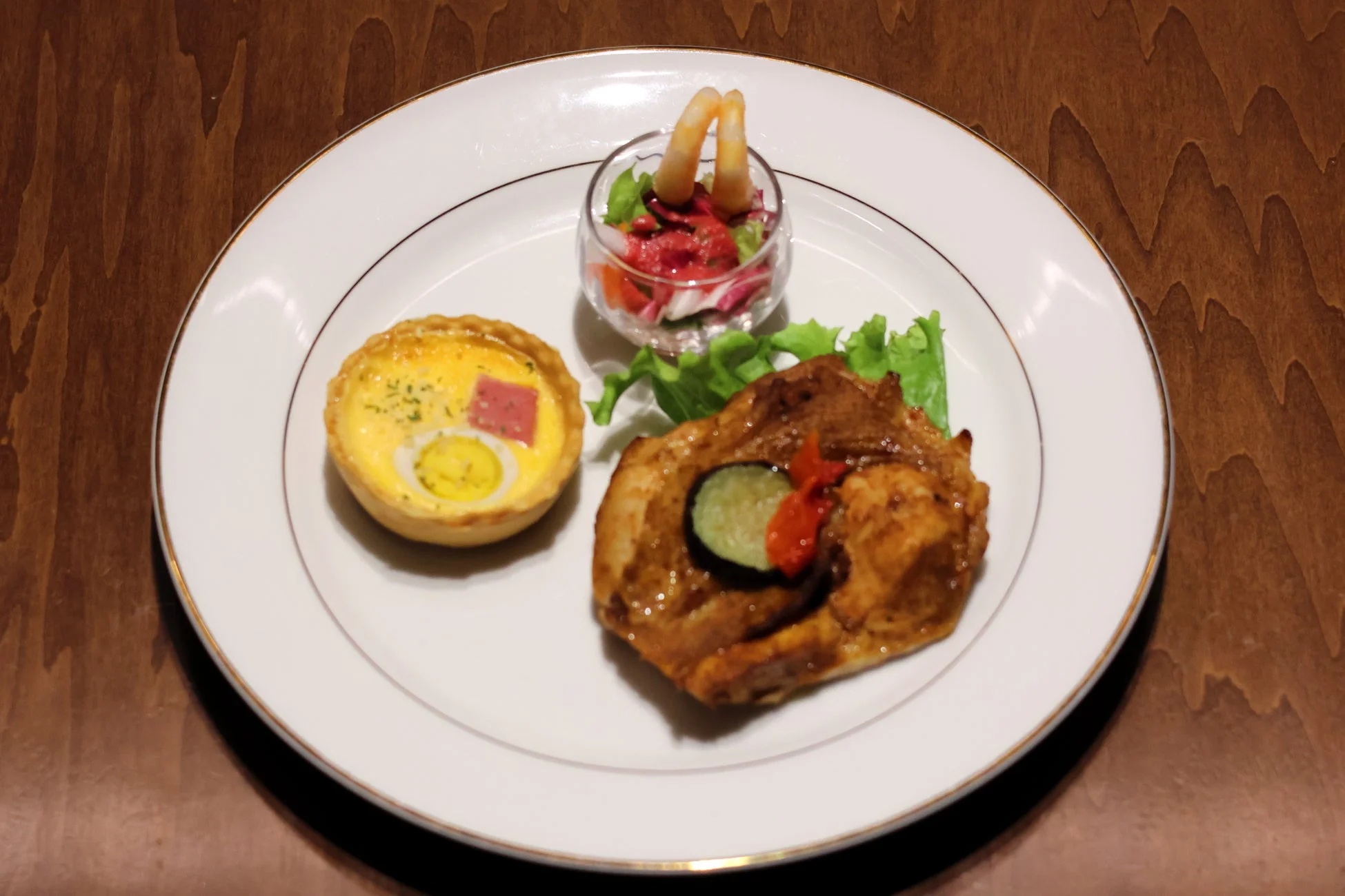 白い皿に盛り付けられた、キッシュ、エビのサラダ、肉料理のセット